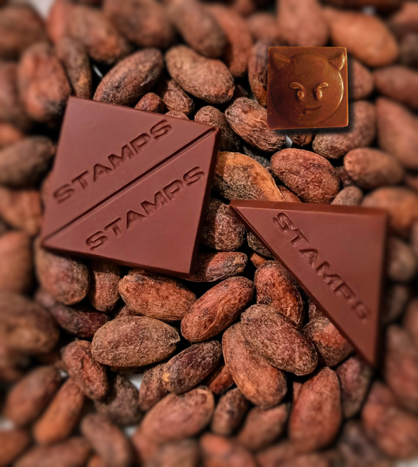 Pieces of Stamps Chocolate on top of cacao beans in the background 